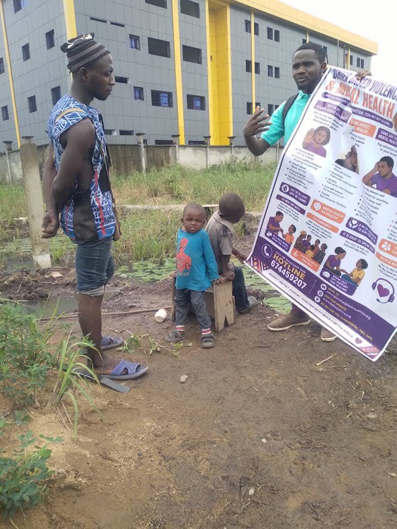 A volunteer explaining the GBV and mental health banner to a community member